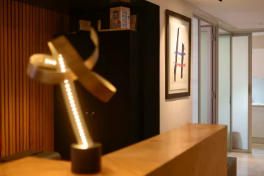 A photograph of the interior of AM Dental Care, showcasing a modern waiting area with a sleek desk, a decorative glowing sculpture, and minimalist artwork on the wall.