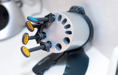 A close-up photograph of a rotating dental composite dispenser and organizer holding multiple labeled composite syringes on a counter.