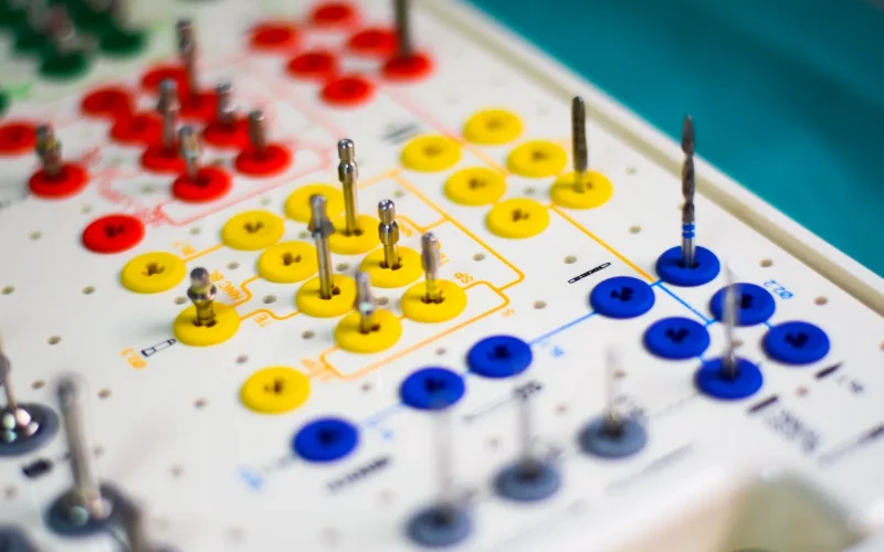 A close-up photograph of an organized dental implant surgical kit featuring color-coded drills and components.