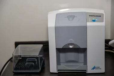 A close-up photograph of a Dürr Dental VistaScan imaging plate scanner and accessory box on a counter in a clinic.