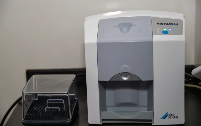A close-up photograph of a Dürr Dental VistaScan imaging plate scanner and accessory box on a counter in a clinic.